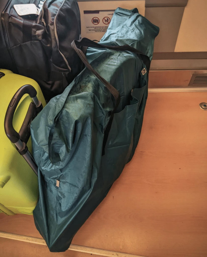 Bike packed in a travel bag, placed upright among other luggage inside a train.